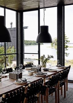 a dining room table set with place settings and black lamps hanging from the ceiling over it