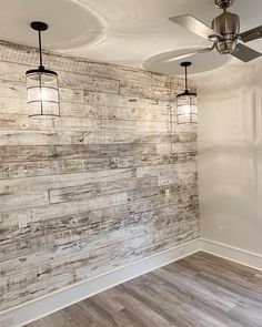 an empty room with wood paneling on the wall and ceiling fan hanging from the ceiling