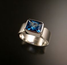 "This gorgeous 8x10mm rectangular Swiss blue Topaz is bezel-set in sterling silver. The Scissors cut stone is eye clean and sparkles with lively Glacier blue color The band measures 2mm thick and 8mm wide. This is a sturdy and comfortable setting that can be worn regularly. I can make this ring in any size between 7 and 13. Specify your ring size in a \"note to seller\" at check-out" Modern Topaz Ring With Rectangular Stone For Formal Occasions, Modern Formal Topaz Ring With Rectangular Stone, Modern Rectangular Sapphire Ring For Anniversary, Modern Rectangular Blue Sapphire Ring, Modern Rectangular Sapphire Anniversary Ring, Modern Square Cut Jewelry With Accent Stones, Modern Blue Rectangular Sapphire Ring, Modern Rectangular Topaz Wedding Ring, Modern Topaz Ring With Accent Stones