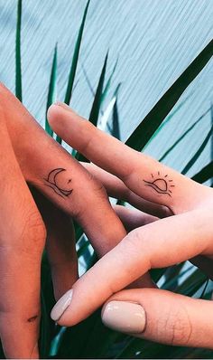 two people holding hands with tattoos on their fingers