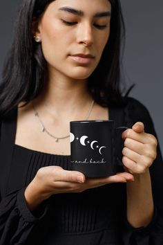 a woman holding a coffee mug with the moon and stars on it in her hands