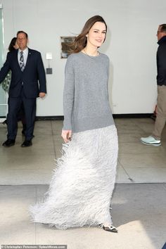 a woman in a gray dress is walking down the street