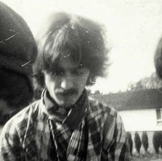 an old black and white photo of a young man with long hair wearing a tie