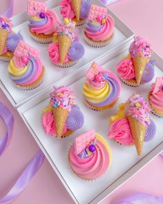 cupcakes decorated with pink, purple and yellow icing on a white tray