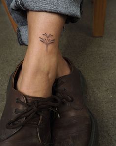 a woman's foot with a small flower tattoo on her left ankle and right leg