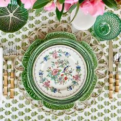 a green and white table setting with pink flowers