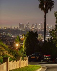 the city lights shine brightly in the distance as cars drive down a street at night