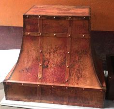 an old fashioned copper colored stove hood with rivets