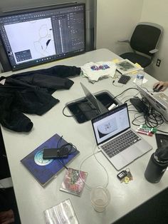 a man sitting at a desk with two laptops and several other electronics on it