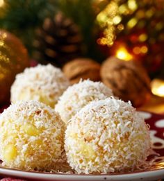 three coconut balls on a plate with christmas decorations in the background