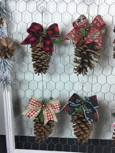 pine cones are hung on the side of a chicken wire fence decorated with bows and ornaments