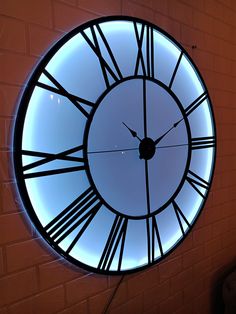 a large clock with roman numerals on the face is lit up at night