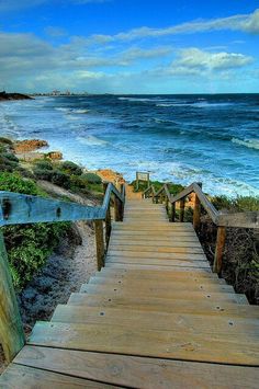 a wooden staircase leading to the beach with an ocean in the background and a quote written on it