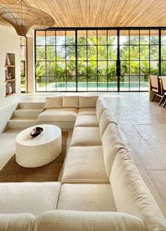 a living room filled with lots of furniture next to a large glass wall window that looks out onto the outdoors