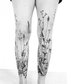 a woman's legs with tattoos on them and flowers growing out of the thighs