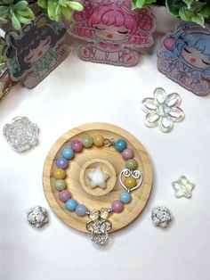 a wooden plate topped with lots of different colored beads and charms on top of a table