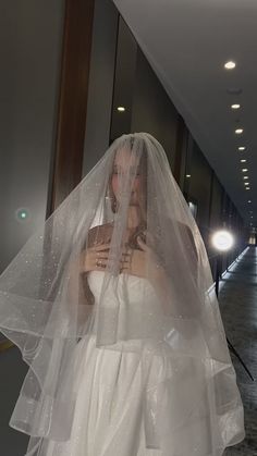 a woman in a wedding dress and veil is posing for the camera with her hands on her chest