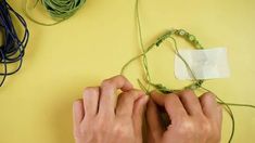 two hands are working on some stringing with scissors and yarn next to the cord