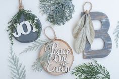 three ornaments are hanging on the wall next to evergreen branches