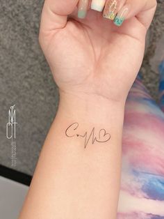 a woman's arm with a heart and heartbeat tattoo on her left wrist that reads cm