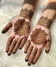 two hands with henna tattoos on them, one is showing the intricate pattern and the other