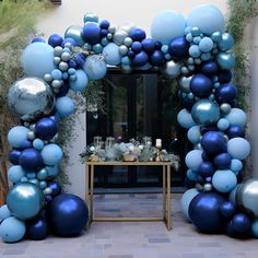 a blue and silver balloon arch is set up for an outdoor party with balloons on it