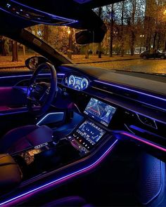 the interior of a modern car with purple lights and dashboard controls, along with an entertainment center