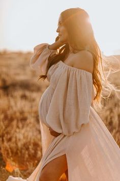 a woman in a white dress walking through a field