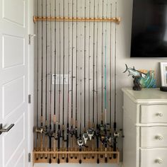 a fishing rod rack is mounted on the wall in front of a white dresser with drawers