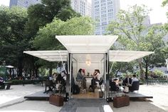 people are sitting at tables in the middle of a park