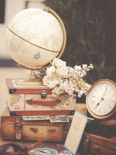 an old world globe sitting on top of suitcases with flowers in the foreground