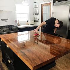 a man in black shirt standing on top of a wooden counter