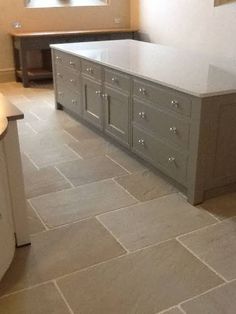 an empty kitchen with grey cabinets and white counter tops