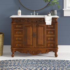 a bathroom with blue walls and a wooden cabinet in the middle, along with a rug on the floor