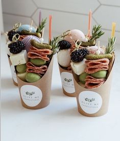 three cups filled with different types of food on top of a white table next to each other