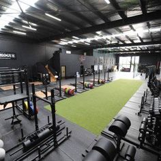 an indoor gym with rows of exercise equipment and green carpeted area for people to use