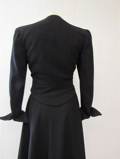 "Vintage 1940s women's suit, jacket and skirt. Made of black rayon/wool. Double breasted military or riding style. Has chrome ball buttons, short cropped, full skirt and pointed turned up cuffs with functional button. Quality construction. No label. Size small. Actual measurements of the jacket: Bust: 34\" waist: 28\" Shoulder seam to shoulder seam: 15.5\" Shoulder seam to cuff: 21.5\" Overall length: 21\" Skirt: waist: 23\" hips: 44\" length: 30\" In excellent condition." Fitted Double-breasted Skirt Suit For Fall, Winter Formal Fitted Skirt Suit, Fitted Skirt Suit With Button Closure For Fall, Fitted Fall Skirt Suit With Button Closure, Semi-formal Fitted Uniform Style Blazer, Semi-formal Fitted Uniform Blazer, Semi-formal Uniform Style Fitted Blazer, Classic Fitted Wool Skirt Suit, Fitted Winter Uniform Blazer