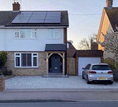 a car parked in front of a house with solar panels on the roof