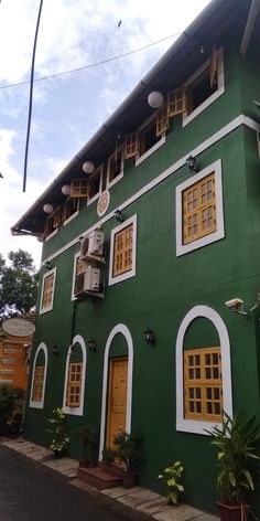 a green building with yellow windows and white trim