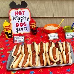 hot dogs on buns with toppings are served at a mickey mouse birthday party