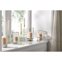 candles are lined up on a window sill