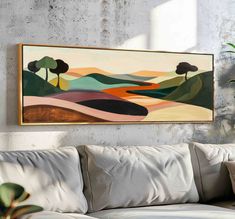 a painting hanging on the wall above a couch in a living room with white walls