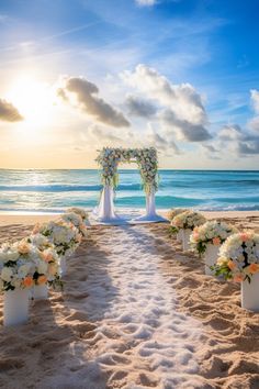 an outdoor wedding setup on the beach with white flowers and greenery in front of the ocean