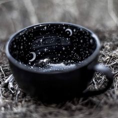 a black cup sitting on top of a grass covered ground with stars and crescents