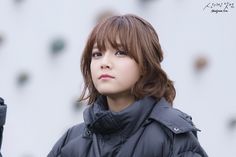 a young woman with brown hair wearing a black jacket and looking off into the distance