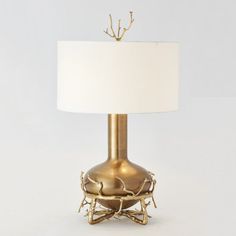 a table lamp with a white shade on it's base and branches around the base