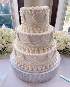 a three tiered wedding cake sitting on top of a table next to white flowers