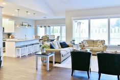 a living room filled with furniture next to a kitchen and dining room table in front of a window