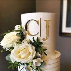 there is a wedding cake with flowers on the top and letters on the side that spell out cj