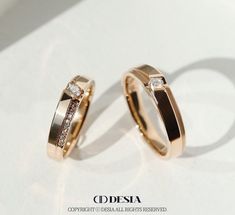 two gold wedding rings with diamonds on them sitting next to each other in front of a white background